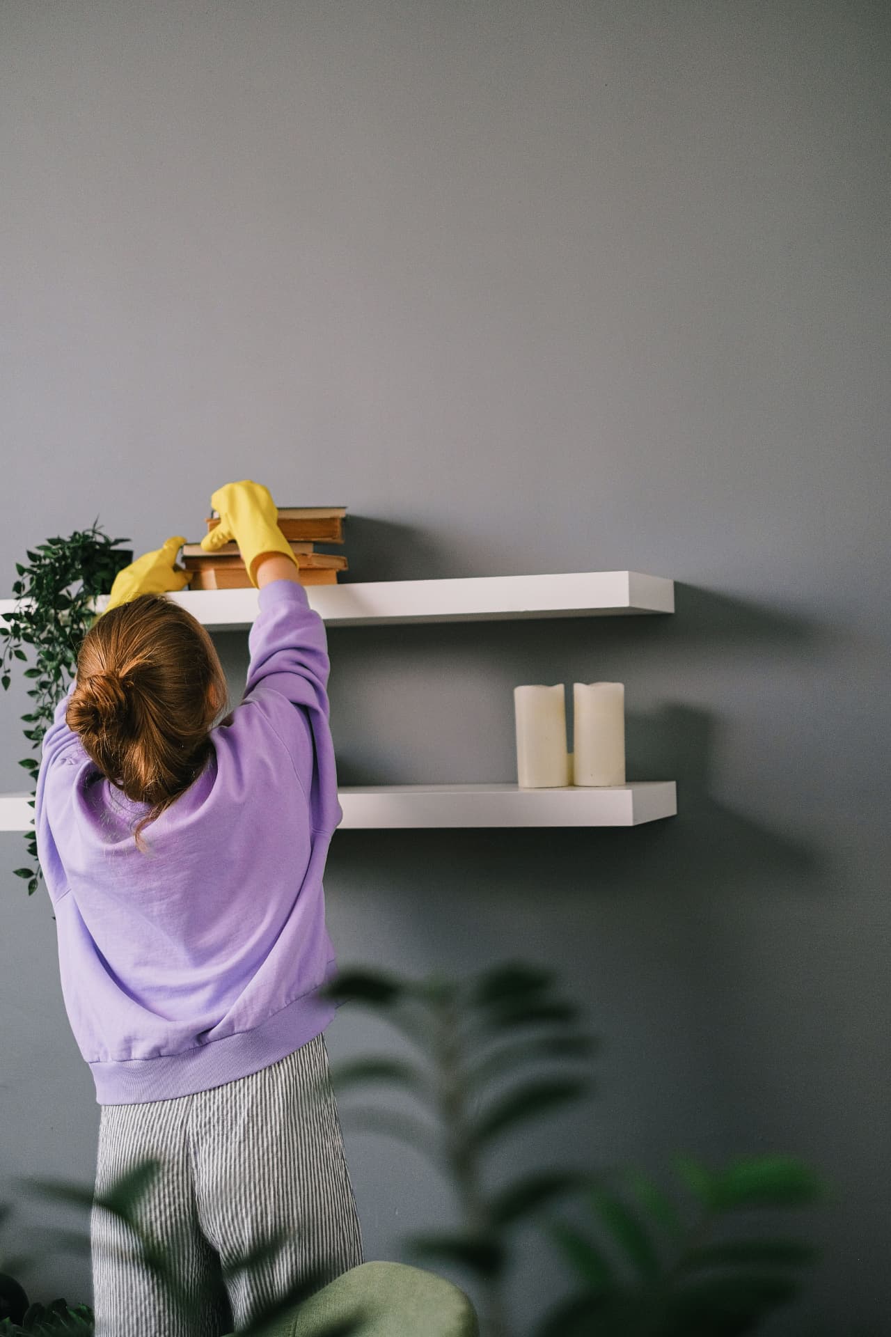 Cleaner dusting floating shelves and books